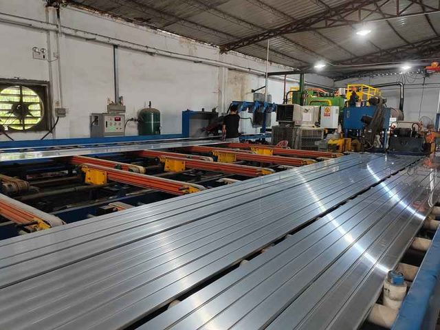Freshly extruded 6063 aluminum profiles on the runout table beside the press